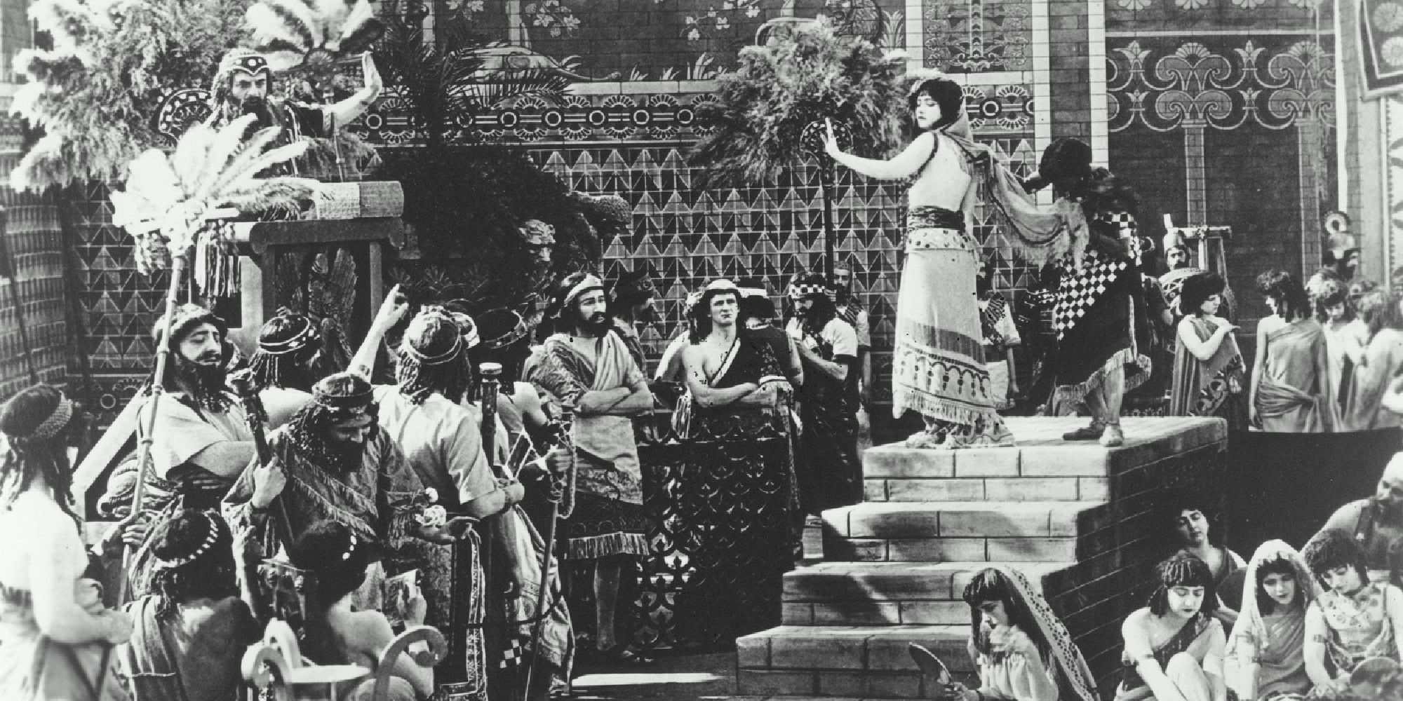 A woman atop a staircase looking back at a crowd in Intolerance