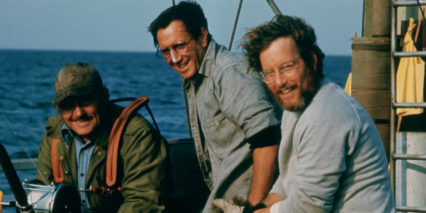 Roy Scheider, Robert Shaw, Richard Dreyfuss sitting on a boat and smiling on the set of Jaws