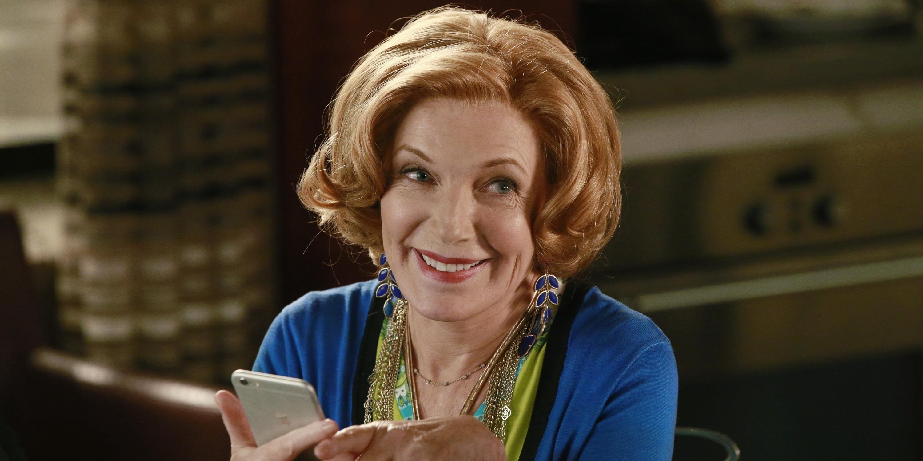 Susan Sullivan as Martha Rodgers, holding an iPhone and smiling on Castle