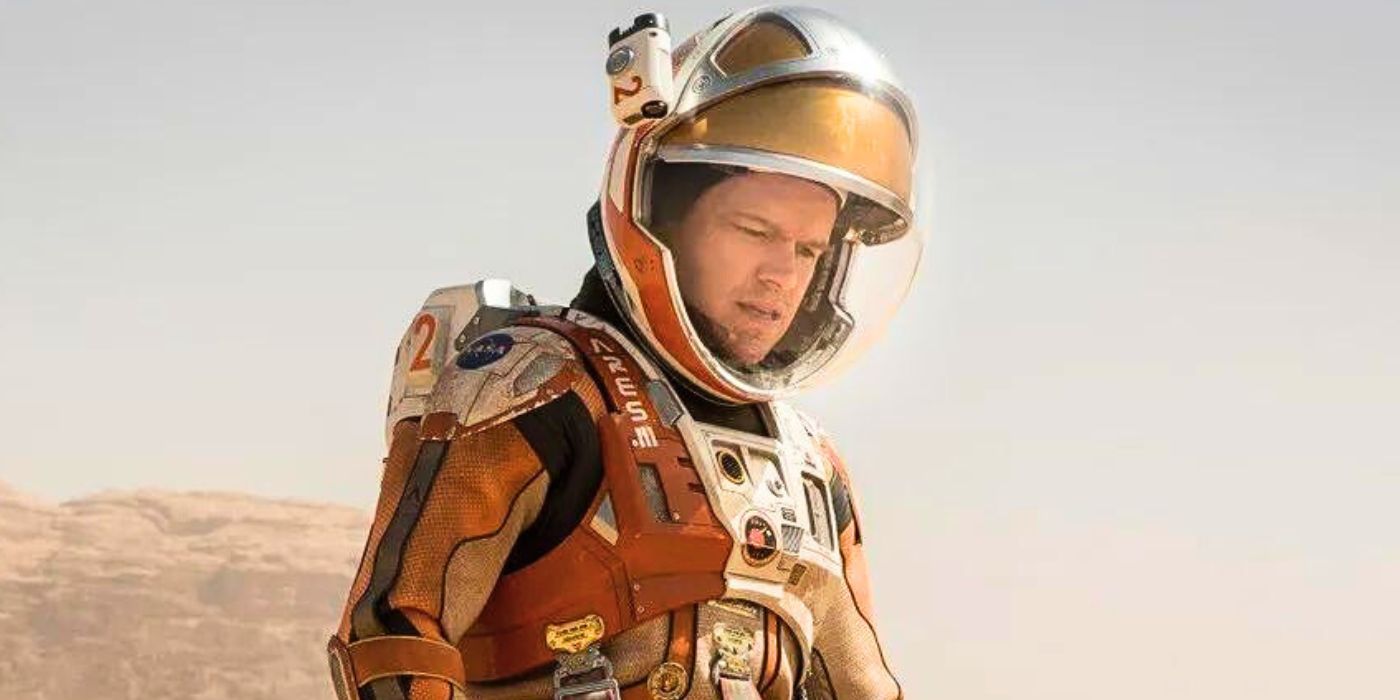 Mark Watney in his spacesuit in Mars looking down in The Martian (2015)