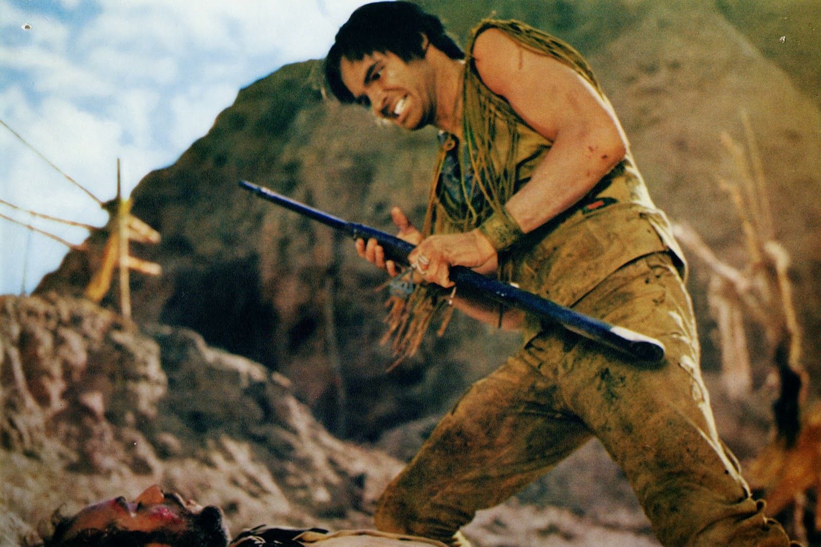 Burt Reynolds without a moustache is standing on a hill with anger in a scene from Navajo Joe