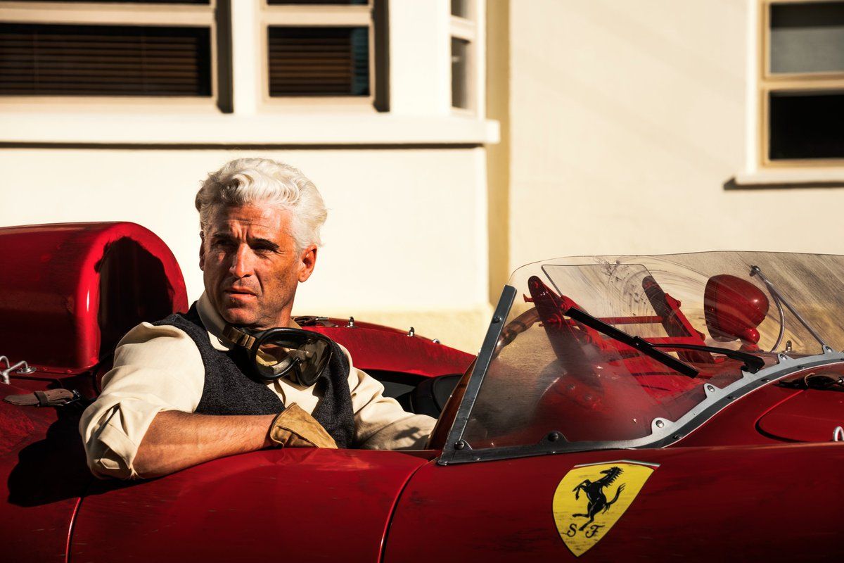 Patrick Dempsey com cabelos brancos sentado em uma ferrari vermelha no filme Ferrari