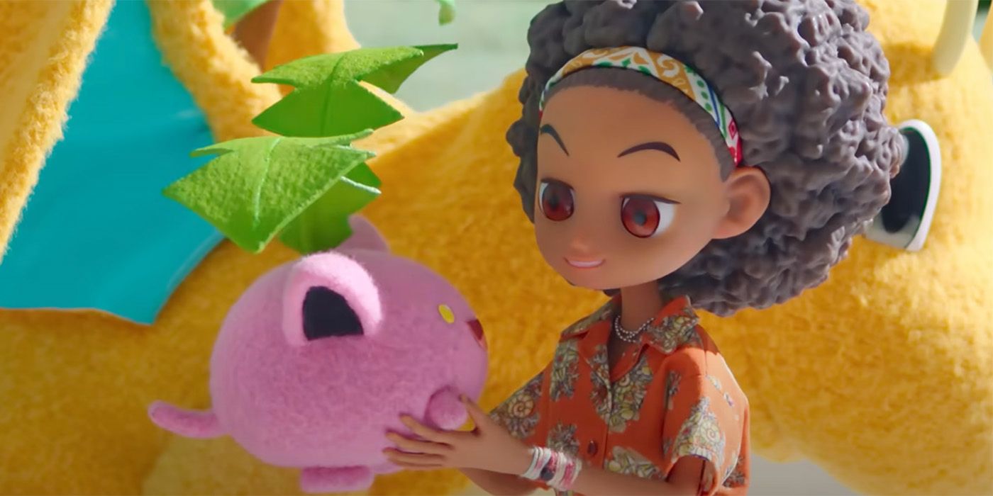 A girl with an afro and an orange t-shirt holding a pink pokemon in Pokemon Concierge
