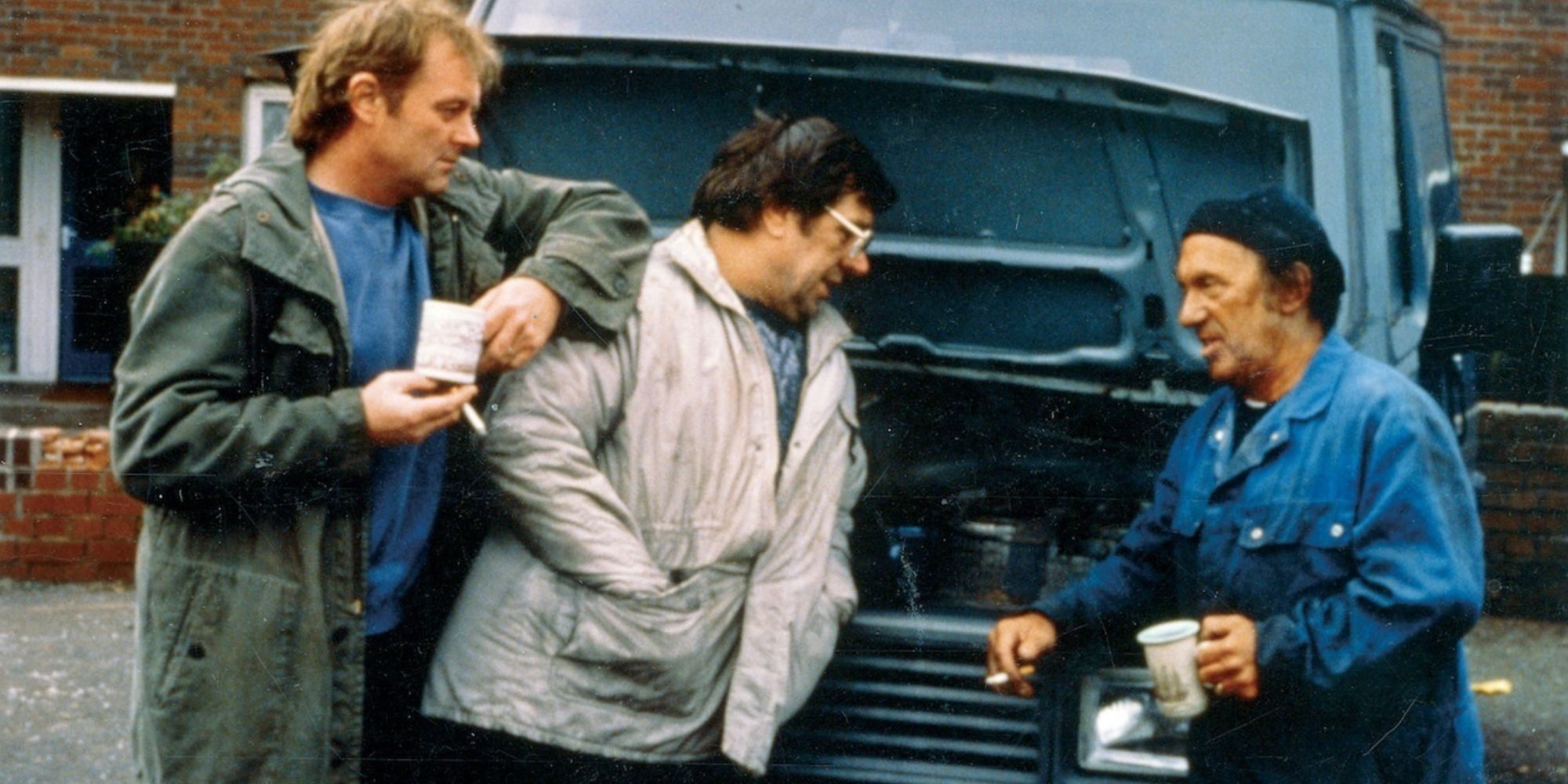 Bruce Jones, Jonathan James e Ricky Tomlinson encostados em um carro em Raining Stones 