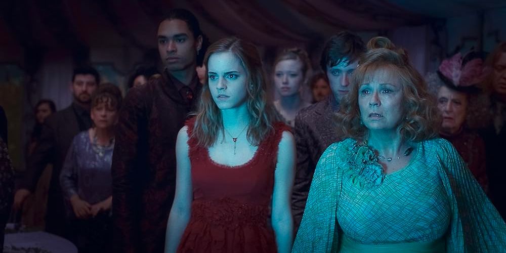 Hermione Granger (Emma Watson) stands with Mrs. Weasley (Julia Walters) before a swarm of wedding guests. 