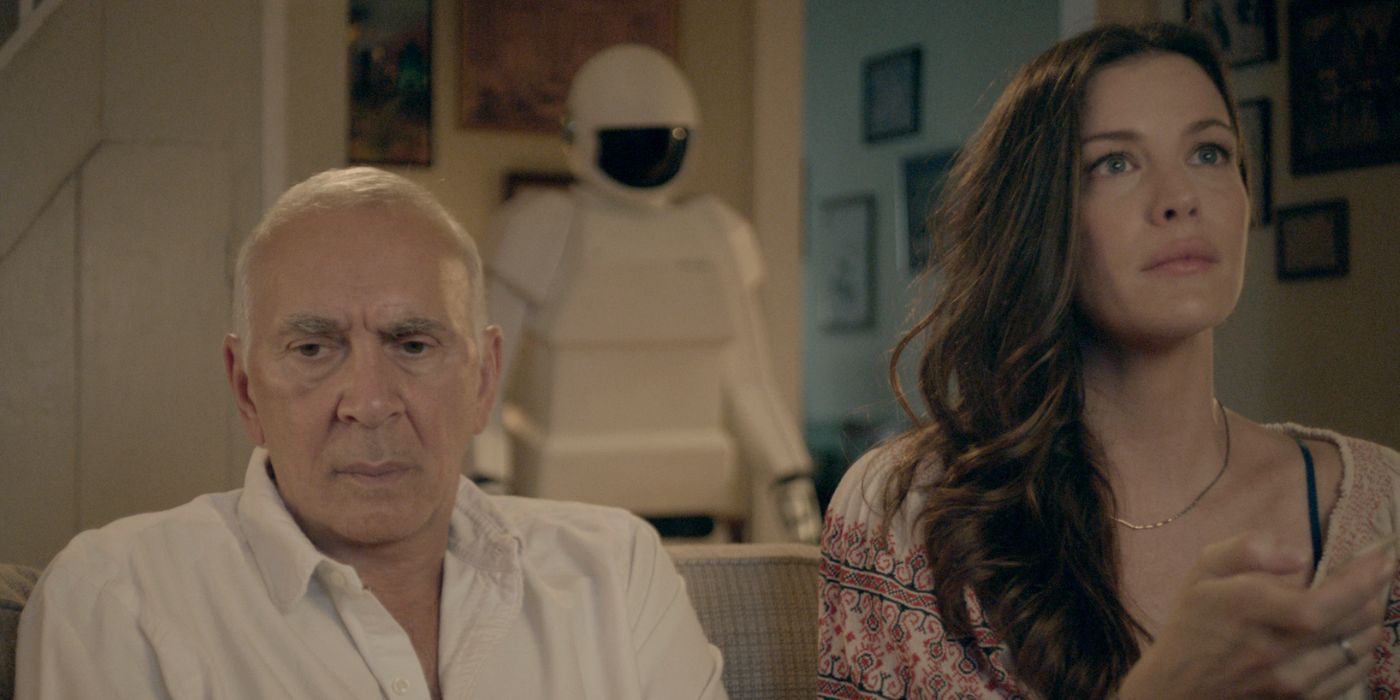 Liv Tyler as Madison and Frank Langella as Frank sitting on a couch with a robot behind them in Robot & Frank