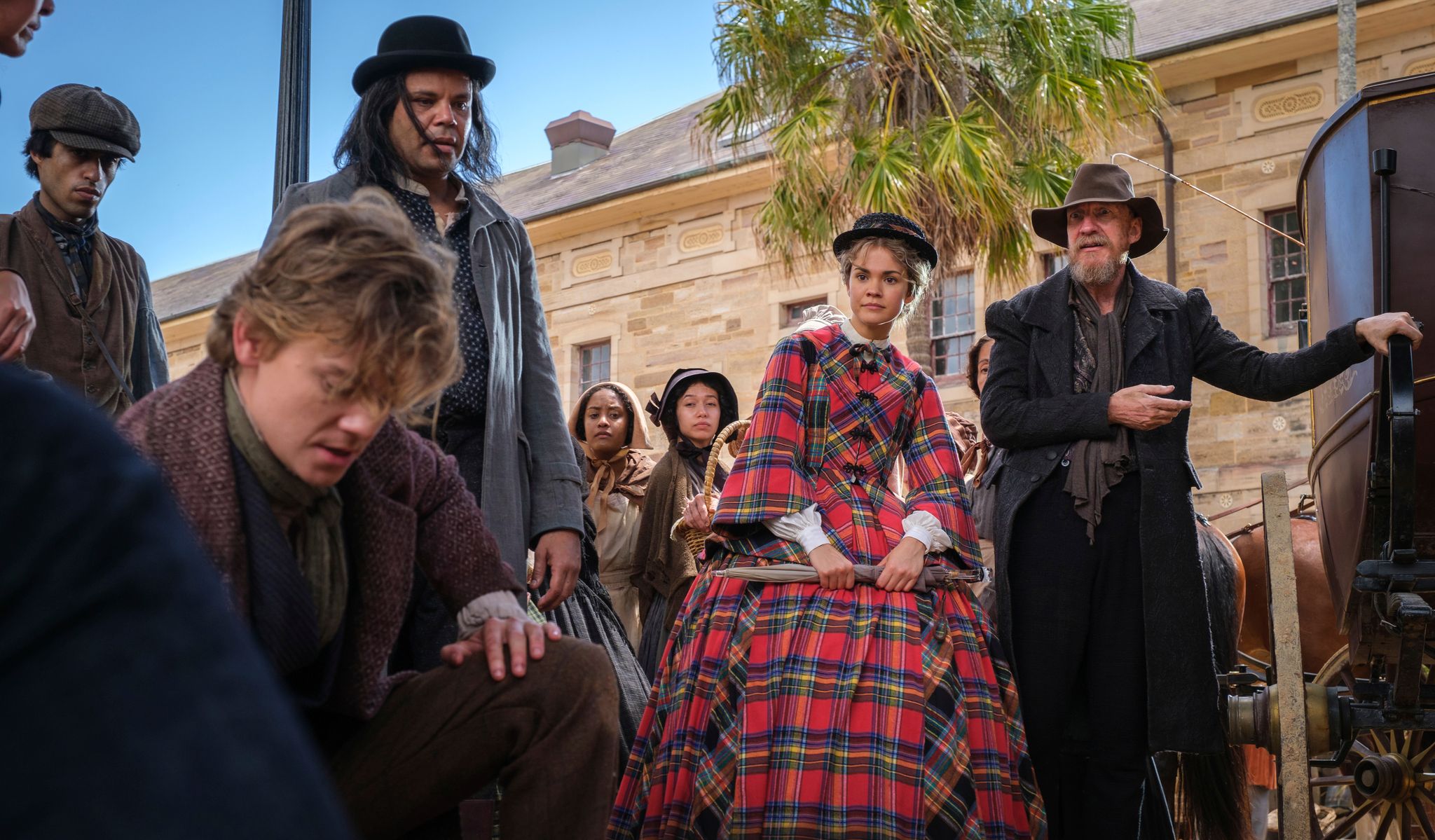 Crowd of people stand outside investigating the ground. Including Jack Dawkins (Thomas Brodie-Sangster), Fagin (David Thewlis), and Lady Belle Fox (Maia Mitchell).
