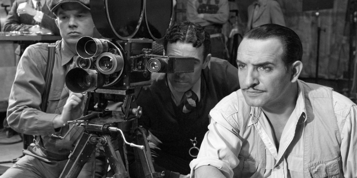 George Valentine next to a film camera looking intently ahead in The Artist