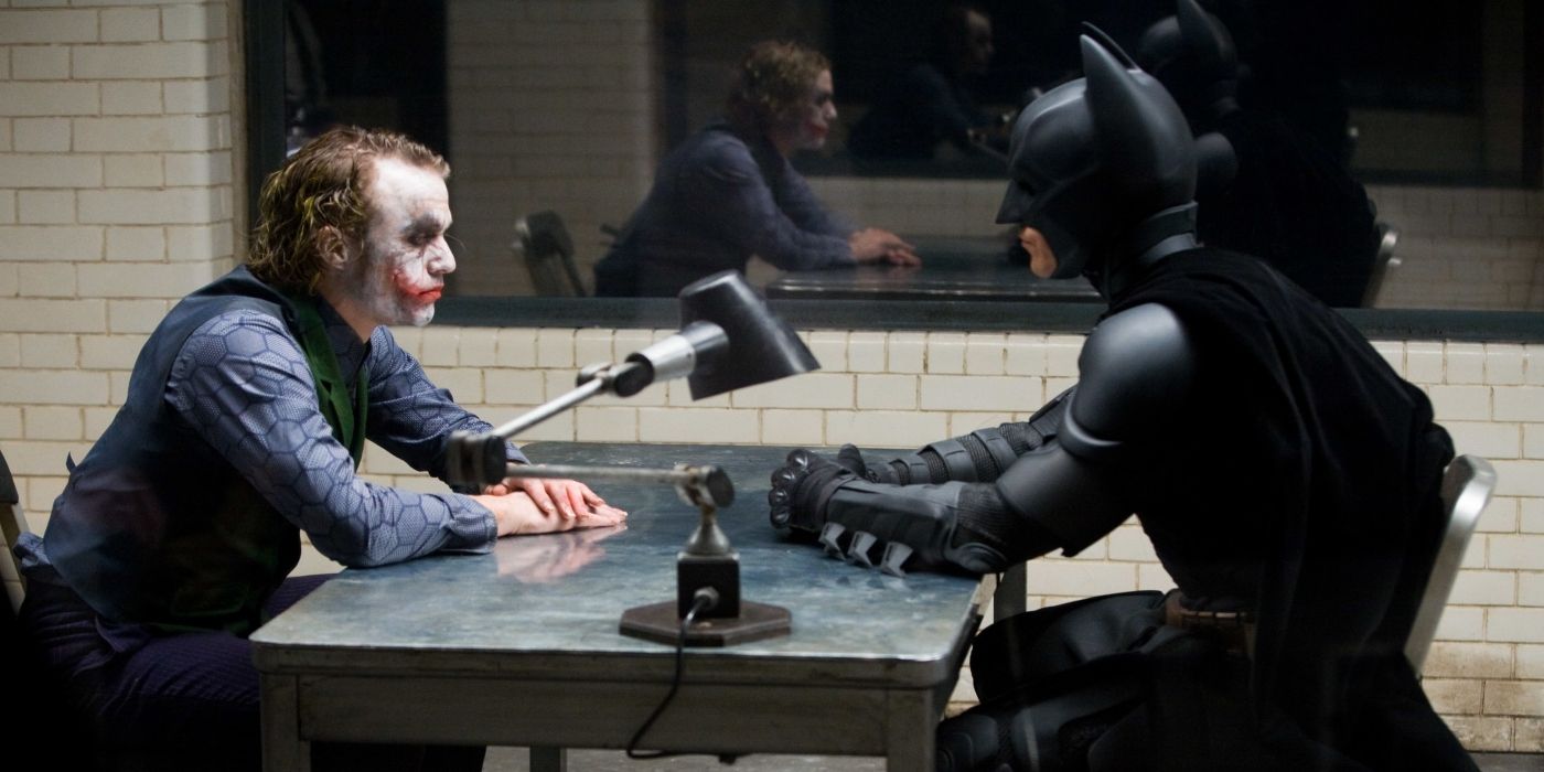 Heath Ledger's Joker sits across from Christian Bale's Batman in an interrogation room in The Dark Knight.