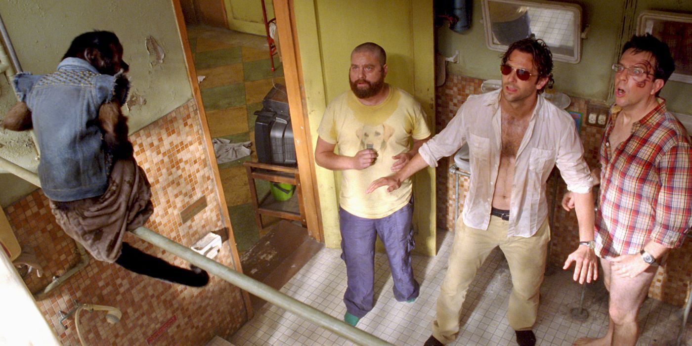 Bradley Cooper, Ed Helms and Zach Galifianakis in The Hangover Part II, looking at a monkey in a hotel room