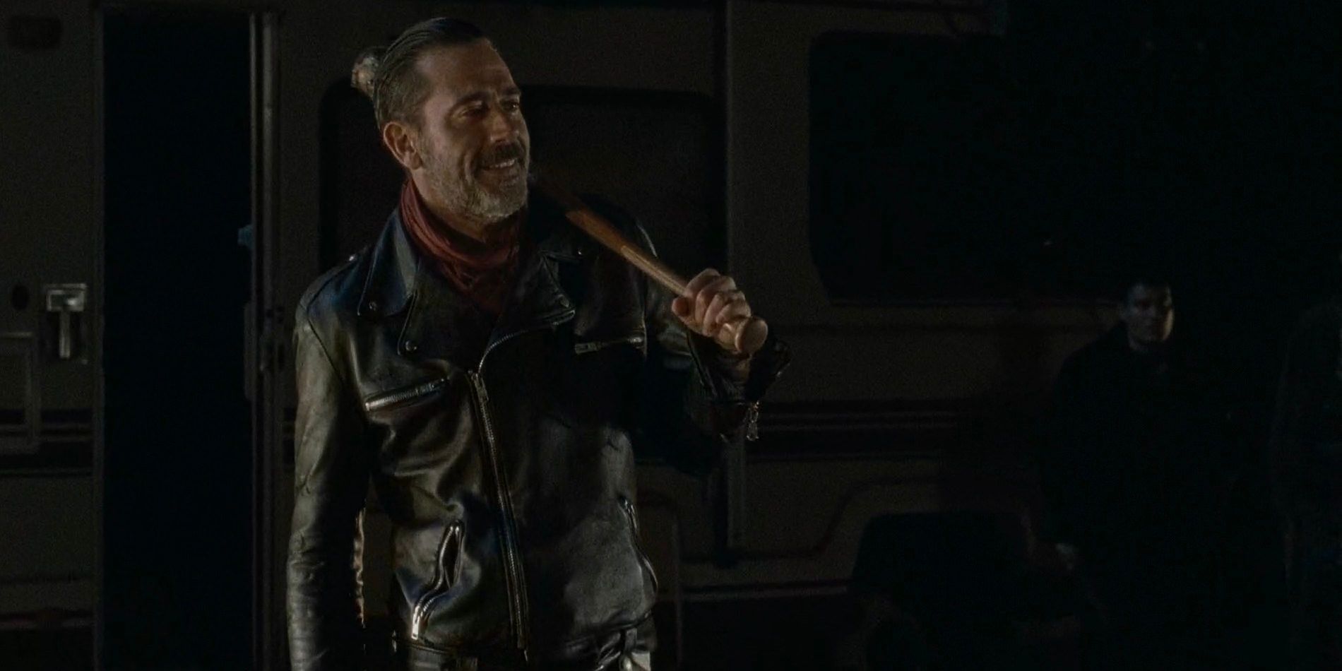 Negan (Jeffrey Dean Morgan) exits his camper van with a wry grin and his baseball bat Lucille over his shoulder. 
