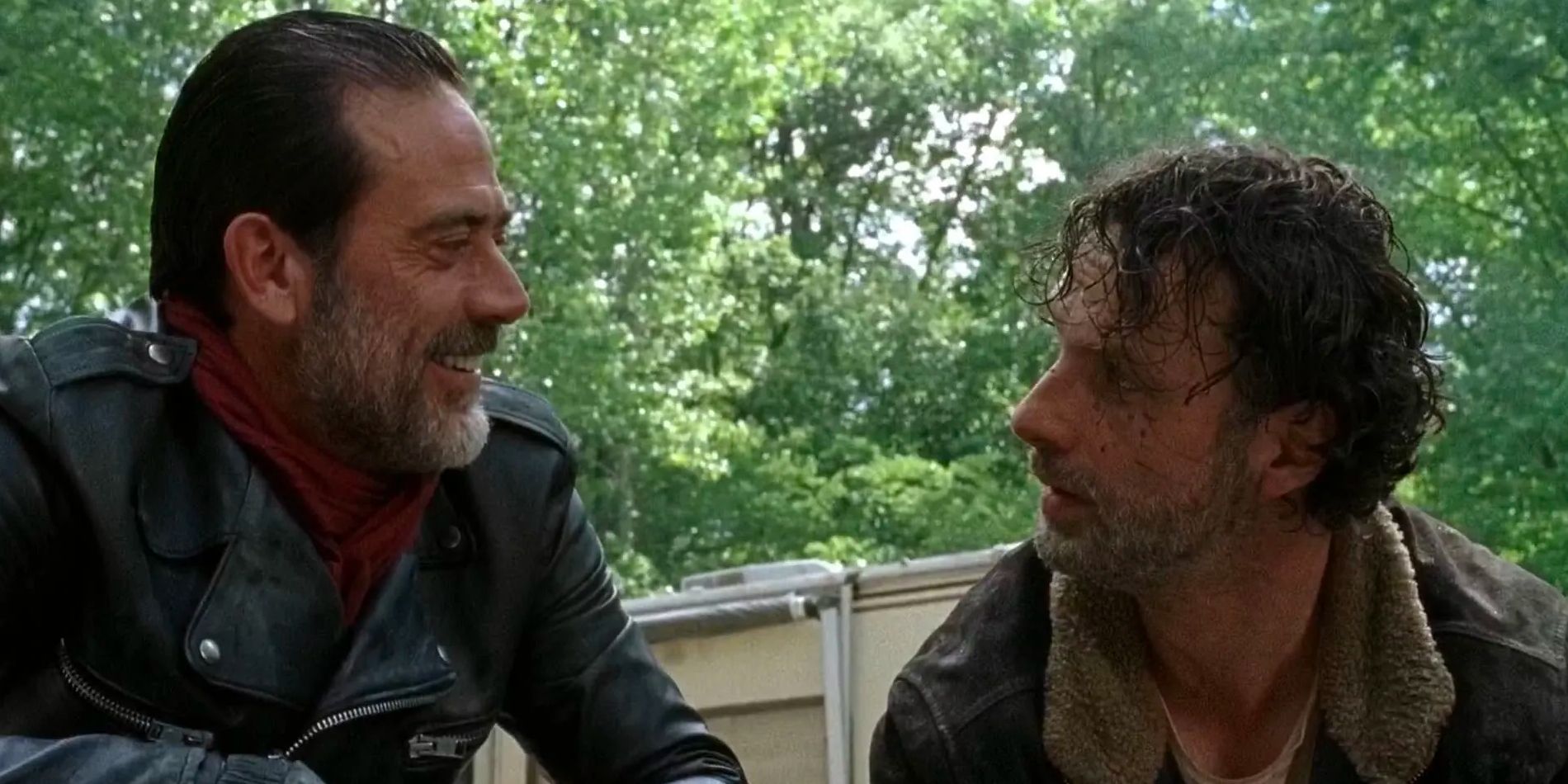 Negan (Jeffrey Dean Morgan) kneels down by Rick (Andrew Lincoln), grinning as he tells him to cut of his son's arm. 