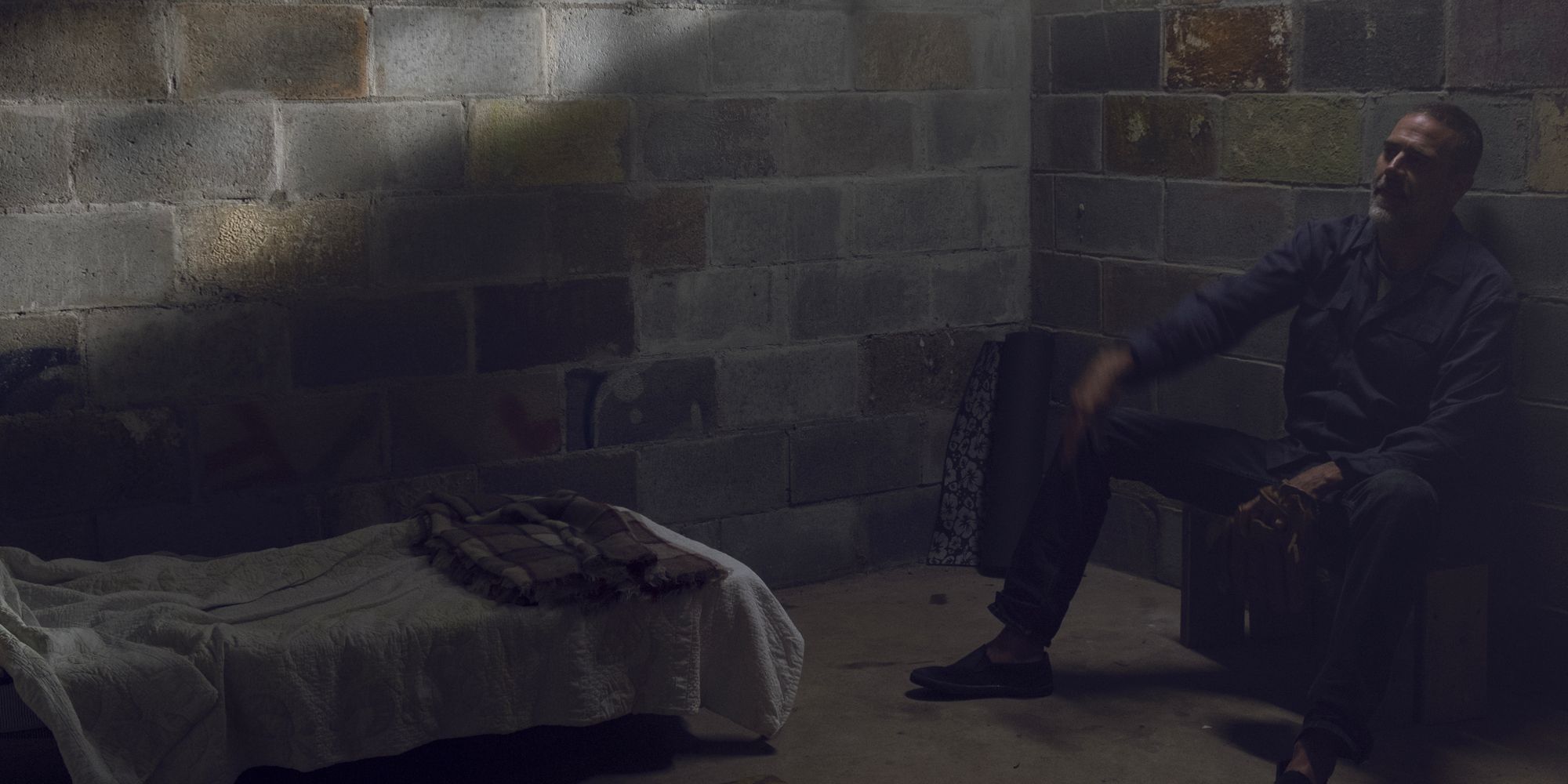Negan (Jeffrey Dean Morgan) throws something while sitting against the wall in his cell in Alexandria.