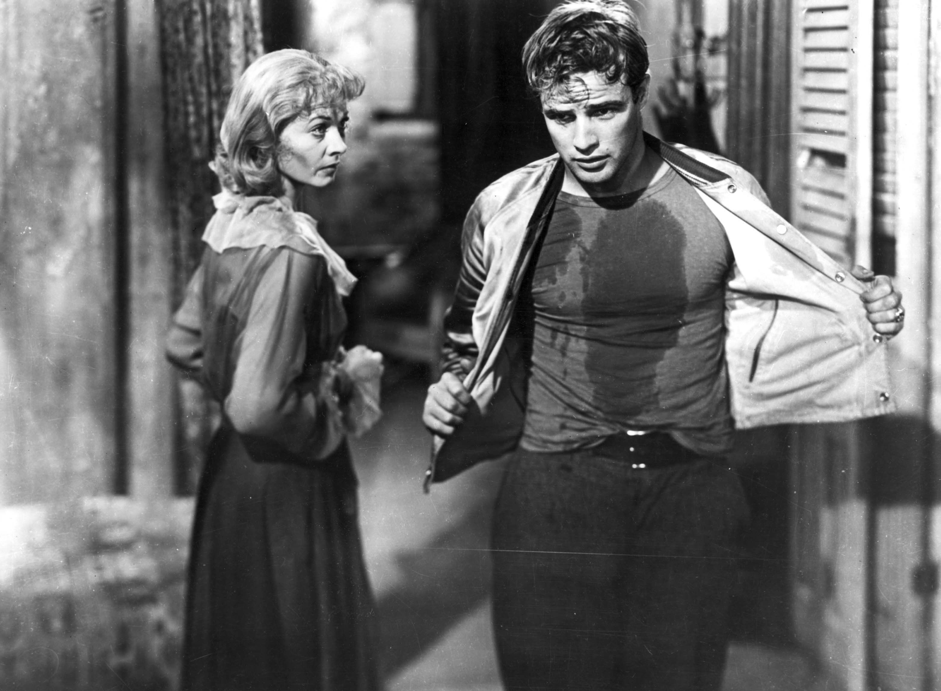 Vivien Leigh as Blanche DuBois and Marlon Brando as Stanley Kowalski taking his overshirt off and covered in grease in A Streetcar Named Desire