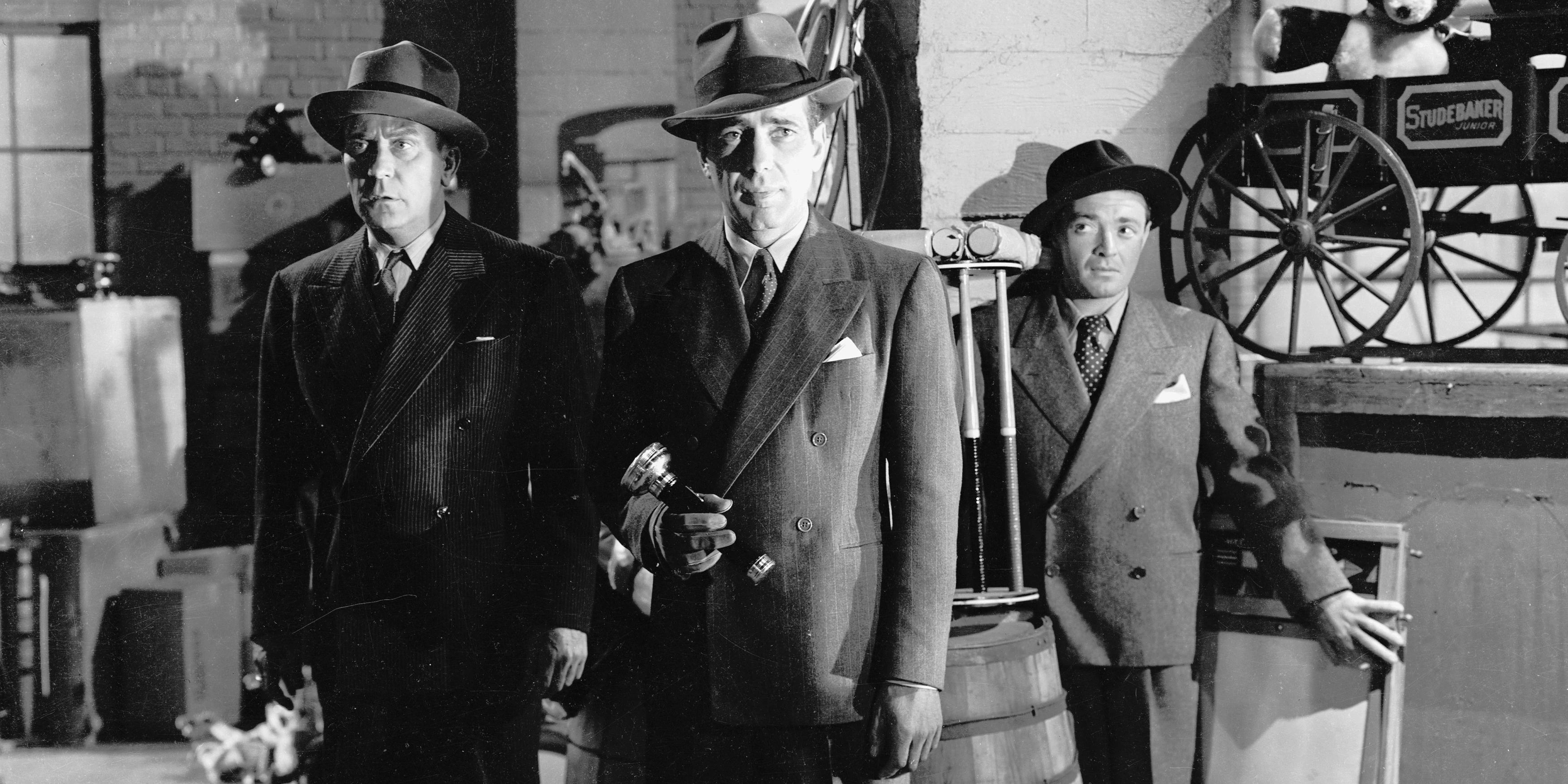 Three men stand in a warehouse with the one in the front holding a flashlight.