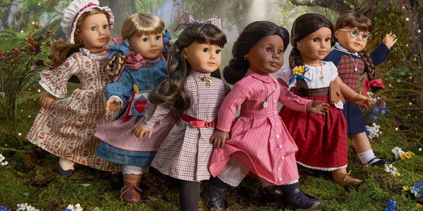 Several American Girl Dolls displayed in a line against a mossy woodland backdrop