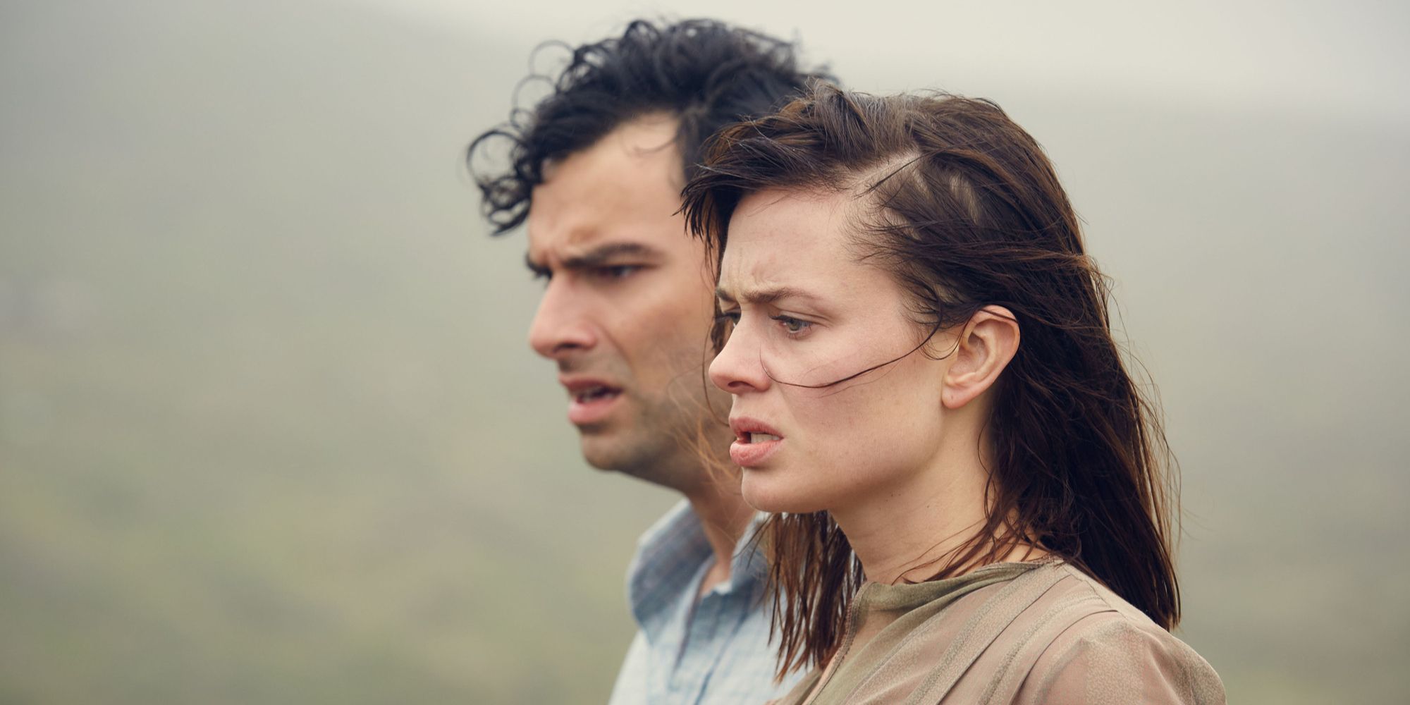 A shoulder high close up of Maeve Dermody as Vera and Aidan Turner as Lombard looking ahead to the left with concerned expressions in And Then There Were None