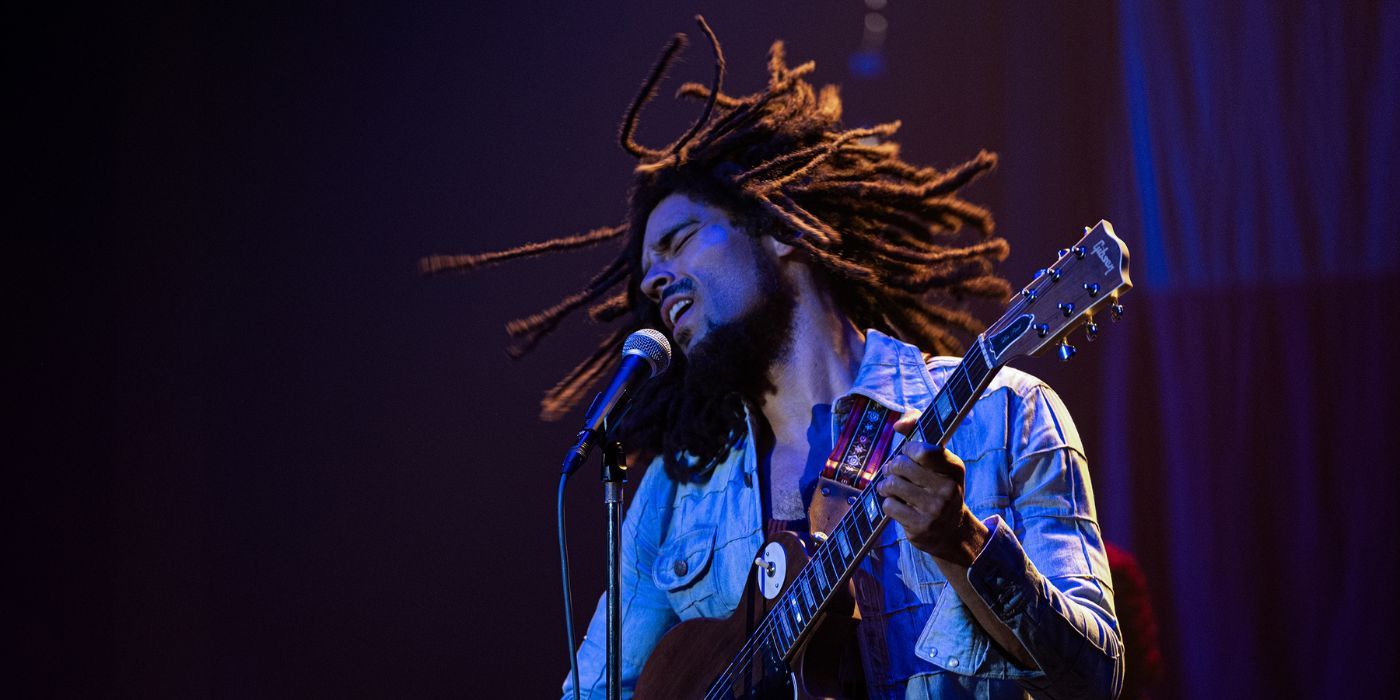 Bob Marley (Kingsley Ben-Adir) performing on the stage with a guitar in Bob Marley: One Love