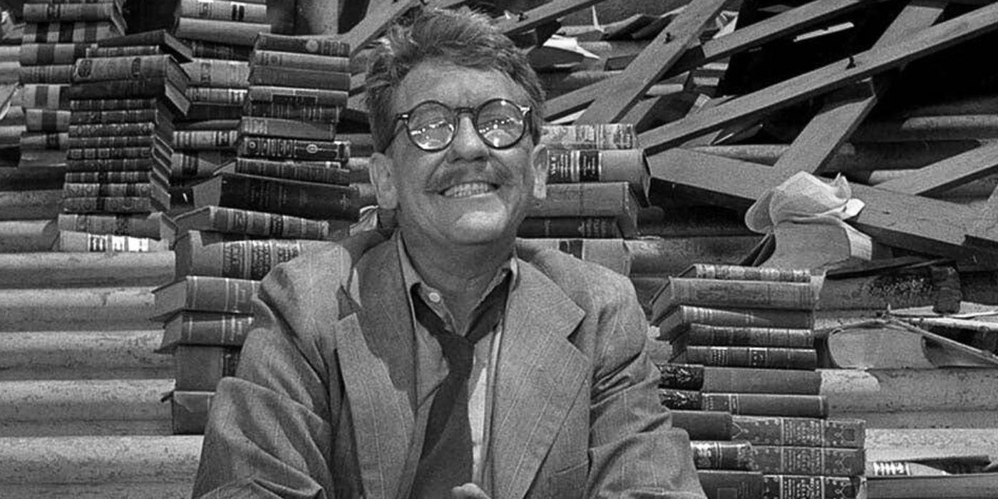 Burgess Meredith as Henry Bemis sitting on steps surrounded by stacks of books in Time Enough At Last from The The Twilight Zone