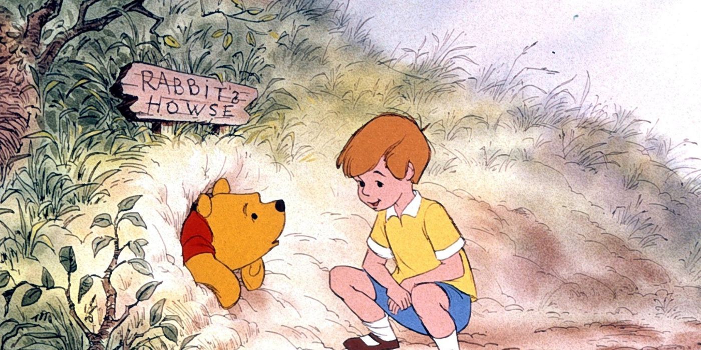 Christopher Robin kneeling as Pooh is stuck in Rabbit&rsquo;s House entrance