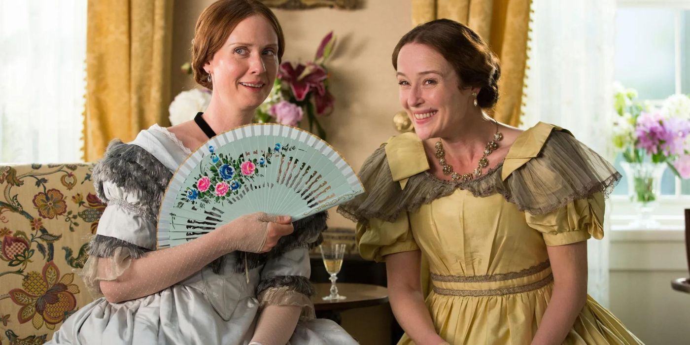 Cynthia Nixon and Jennifer Ehle as Emily and Vinie Dickinson smiling from a couch in A Quiet Passion