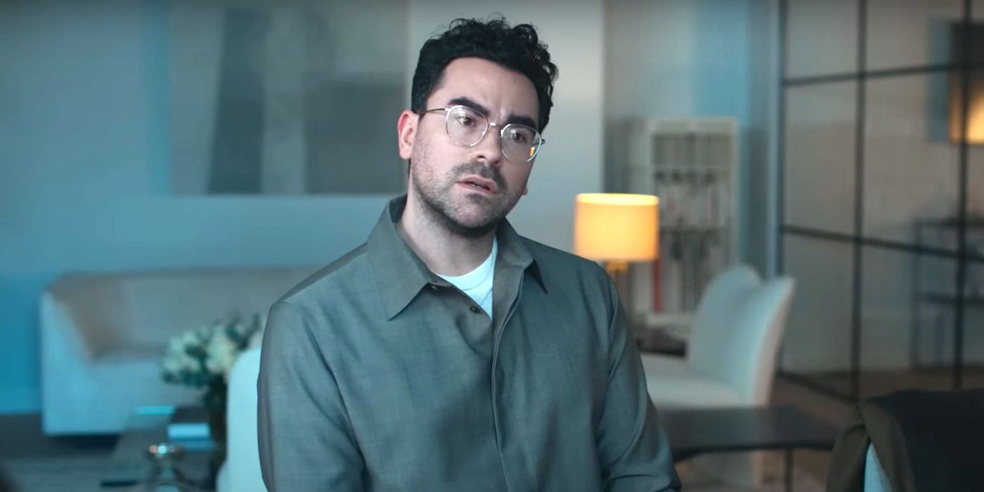 Dan Levy as Marc Dreyfus sitting and talking to someone offscreen in Good Grief