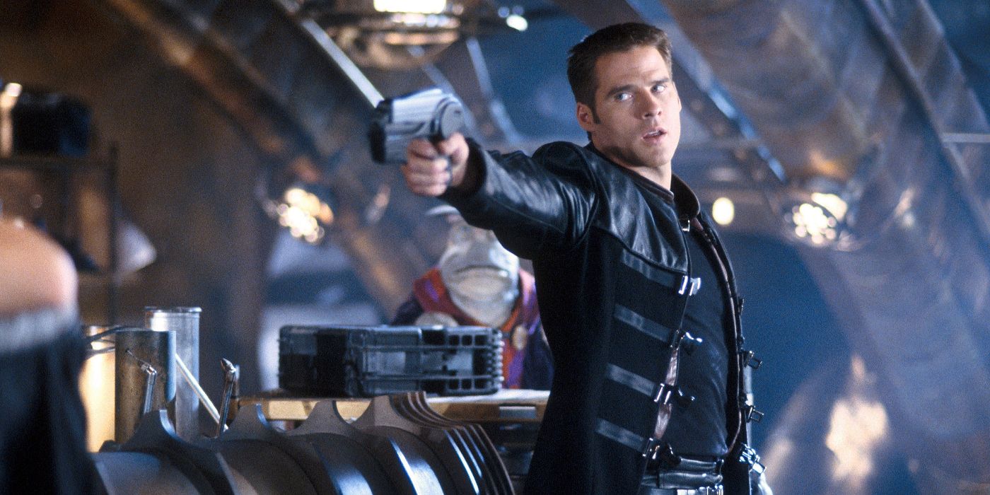 A waist up shot of Ben Browder as John Crichton aiming his pulse pistol weapon to the left on Farscape