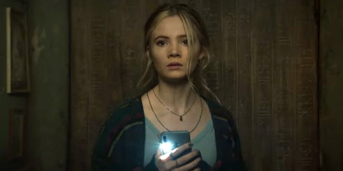 Freya Allen holds a phone with the torch light on in Baghead (2023)
