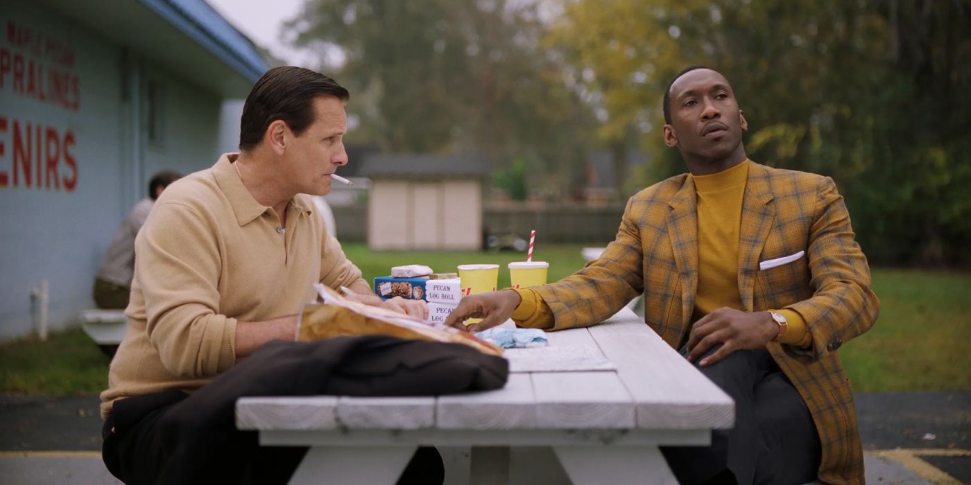 Viggo Mortsensen and Mahershala Ali as Tony and Don talking and having a snack at a picnic table.