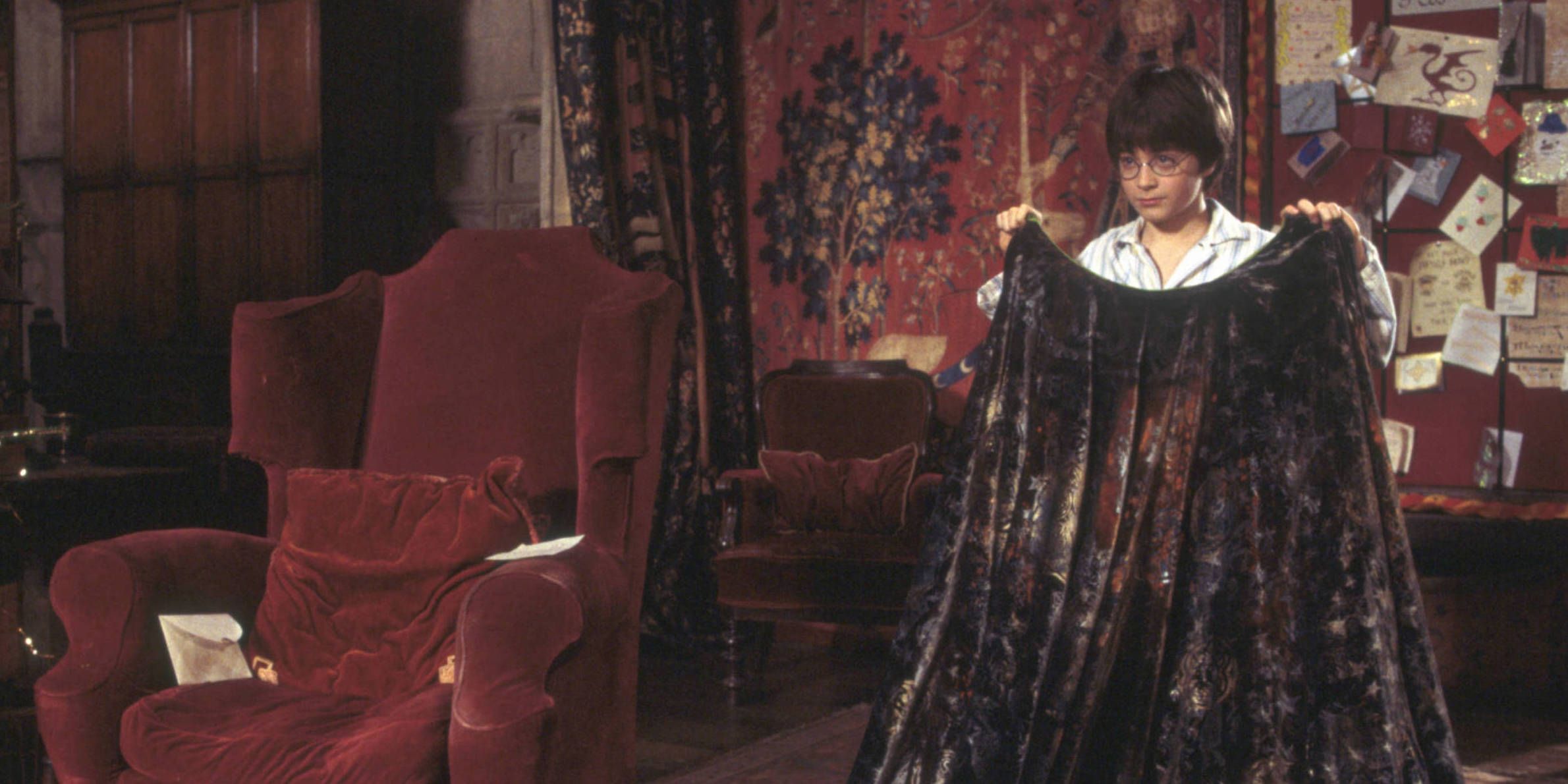 Actor Daniel Radcliffe as Harry Potter, putting on his invisibility cloak in Harry Potter and The Sorcerer's Stone