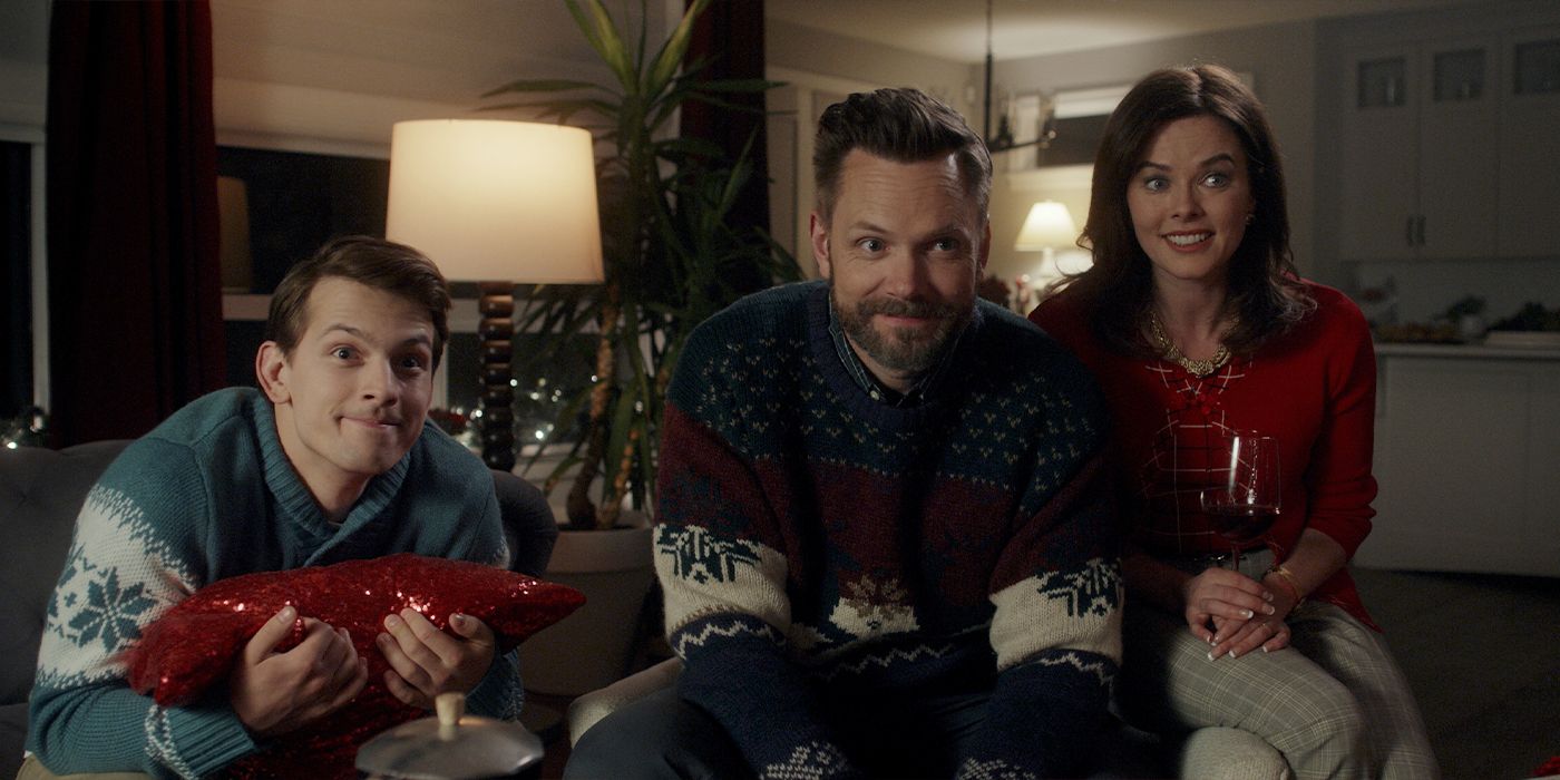 Joel McHale plays David Carruthers in a scene from It&rsquo;s a Wonderful Knife, while wearing a Christmas sweater. He is surrounded by a teenage boy and a middle-aged woman drinking wine.