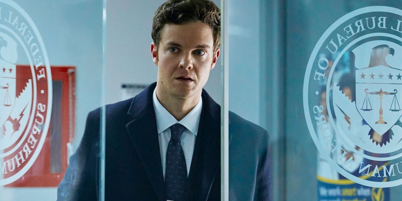 Jack Quaid as Hughie Campbell walking through a glass door in The Boys