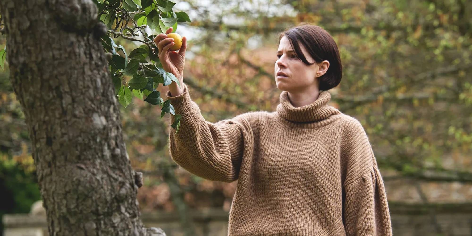 Harper holding a piece of fruit hanging from a tree in Men
