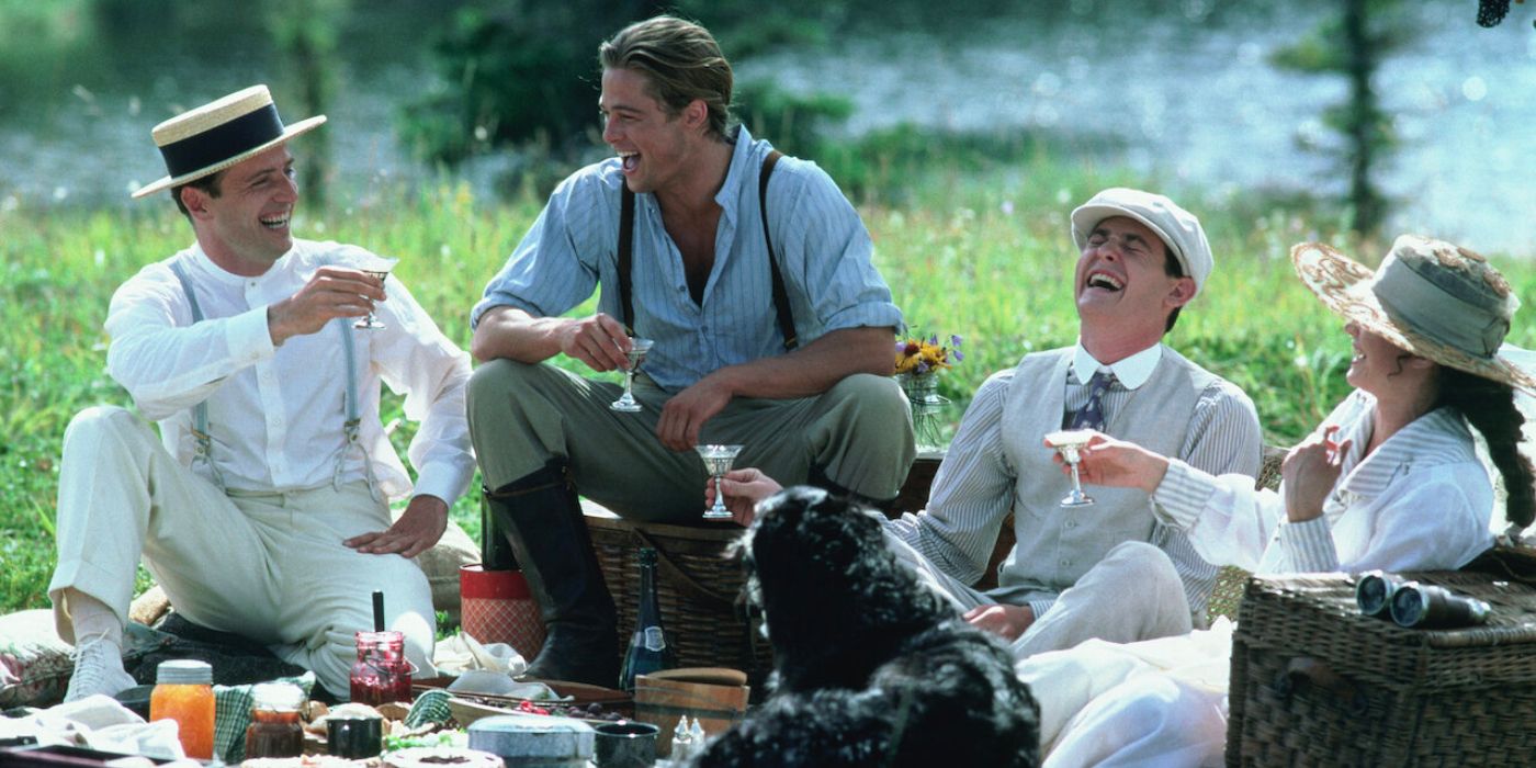 Three brothers and the fiance to one of them sit outside enjoying a picnic by a stream on a perfect day.