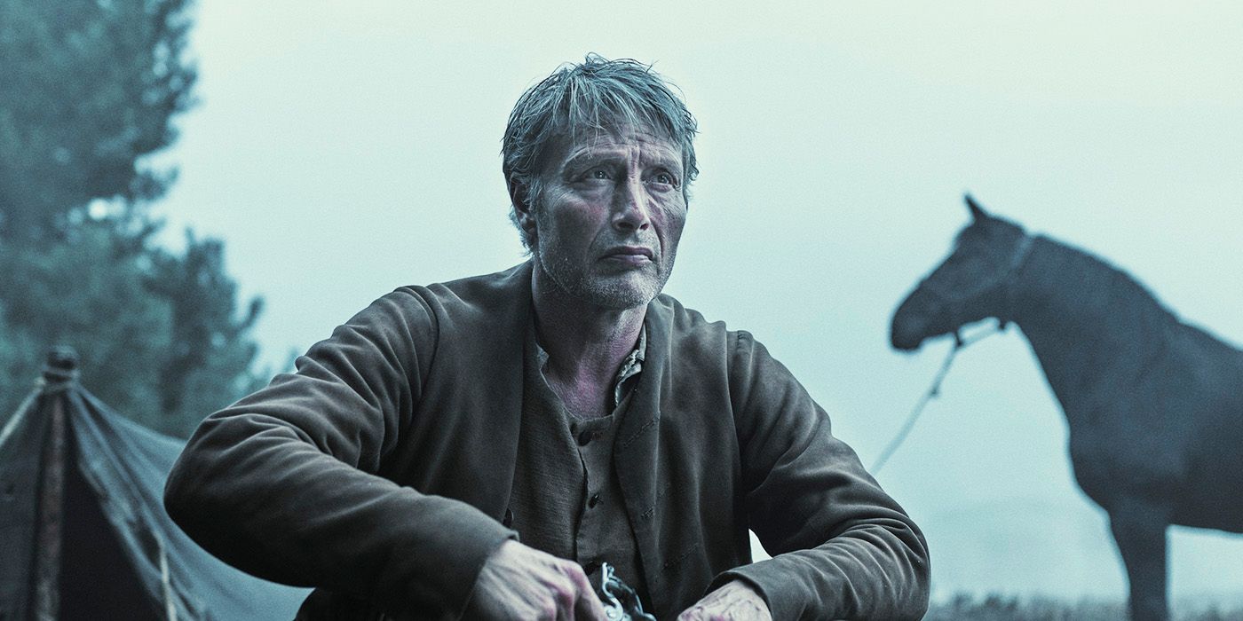 Mads Mikkelsen sitting outside in front of a horse and tent in The Promise Land 