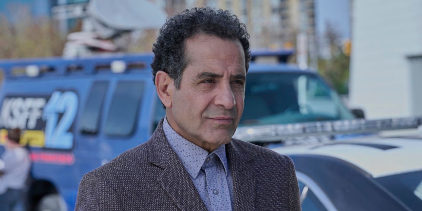 Adrian Monk (Tony Shalhoub) standing in front of a blue news van in Mr. Monk's Last Case: A Monk Movie.