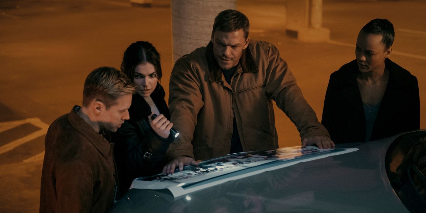 O'Donell (Shaun Sipos), Dixon (Serinda Swan), Reacher (Alan Ritchson), and Neagley (Maria Sten) look at a company picture on the hood of a car in Reacher Season 2