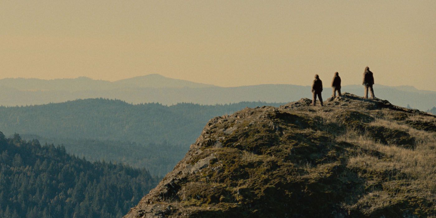 A still from Sasquatch Sunset where three figures look out on the horizon. 
