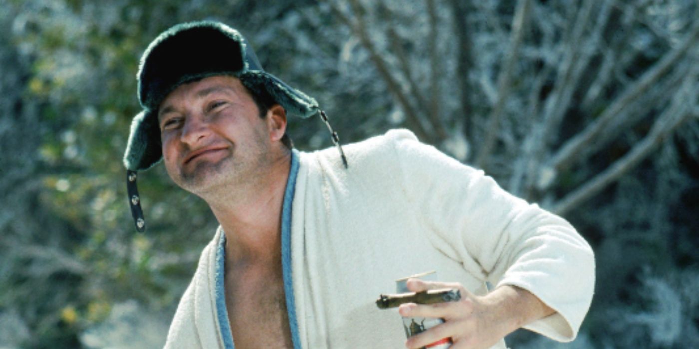 Randy Quaid as Cousin Eddie holding a cigar and beer and wearing a robe in 'Christmas Vacation'
