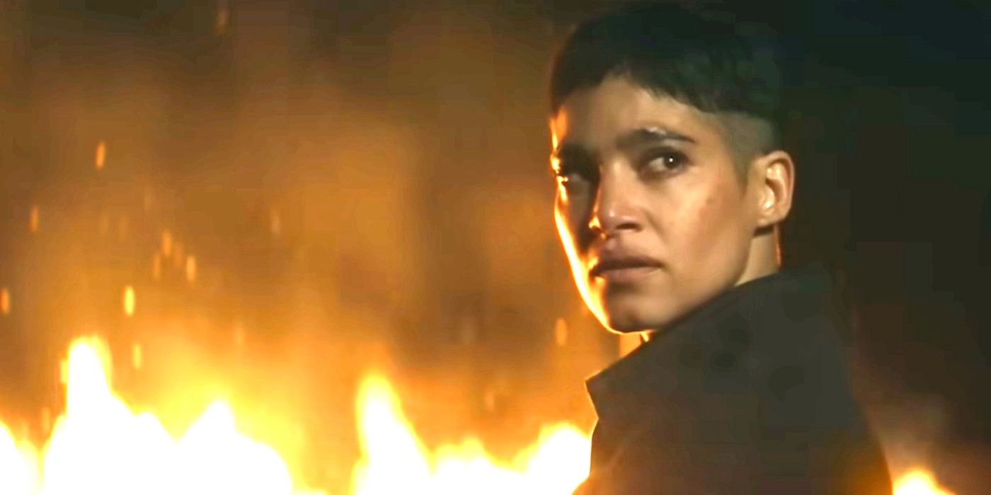 Sofia Boutella as Kora looking back while standing in a burning field in Rebel Moon Part 2