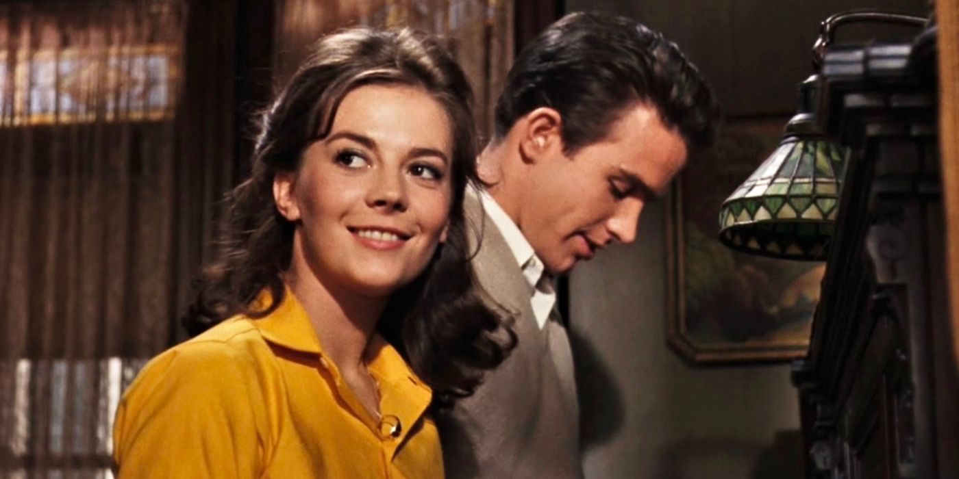 Natalie Wood as a teenage girl smiles while her boyfriend (Warren Beatty) stands beside her, smiling as he looks down.