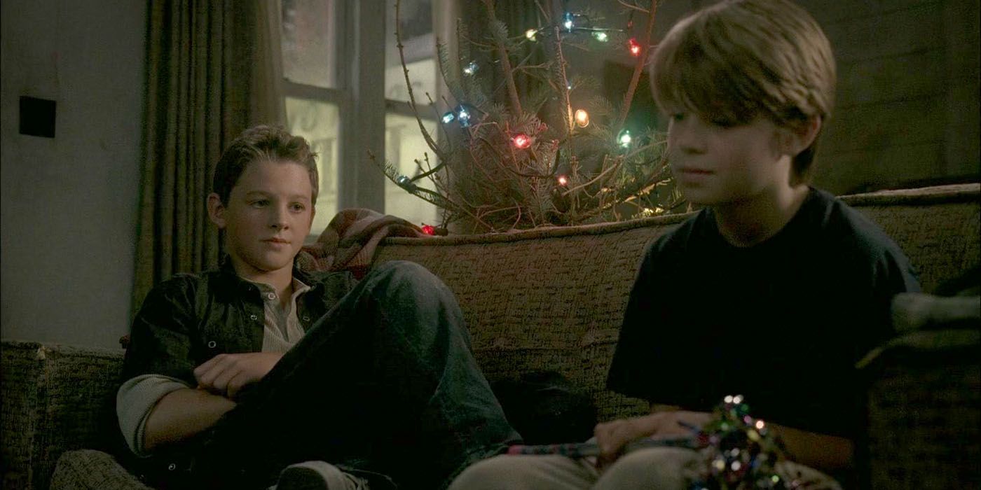 Young Sam and Dean Winchester sit on a couch near a Christmas tree