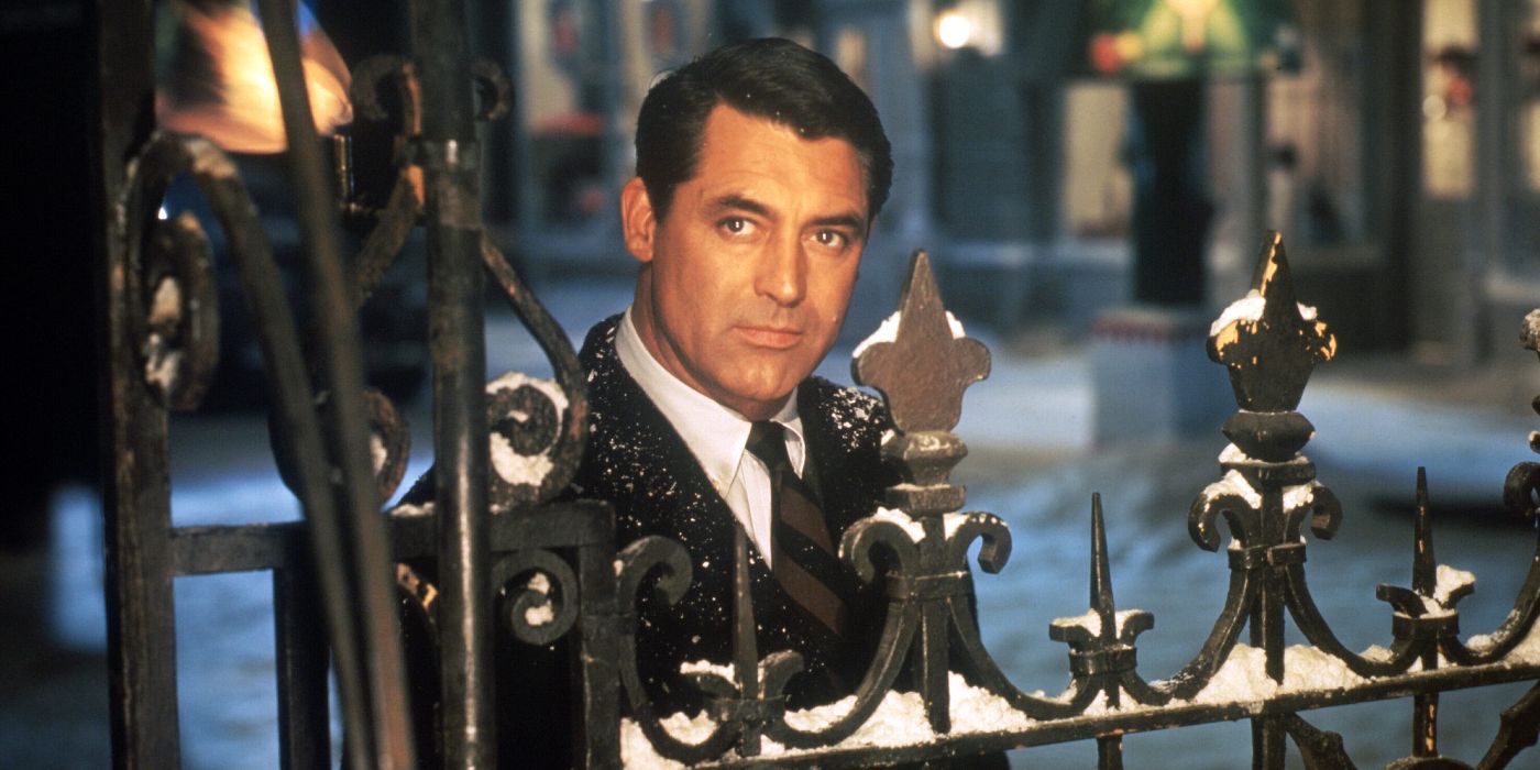 A full color image of Cary Grant standing outside a gate and staring to the left with a snowy street behind him in The Bishop's Wife