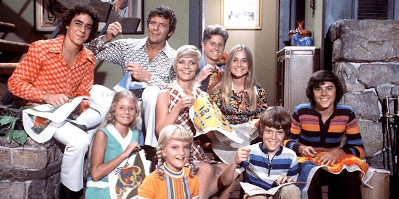 The cast of 'The Brady Bunch' sitting at the base of their iconic staircase.