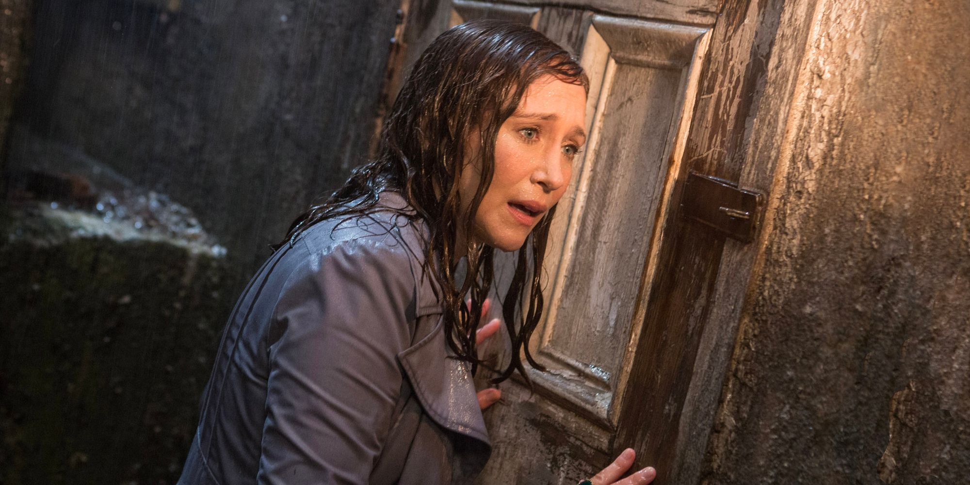 Paranormal investigator and demonologist Lorraine Warren (Vera Farmiga) stands in the rain as she tries to get into a house.