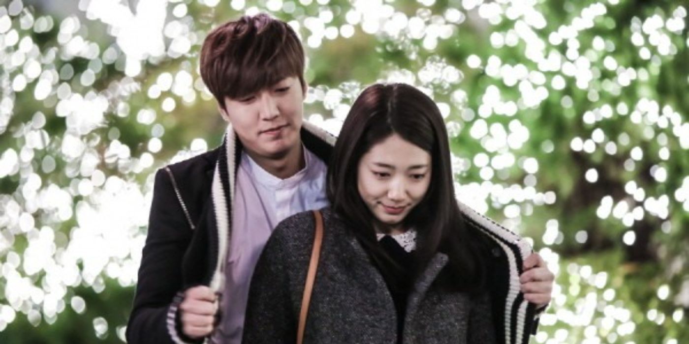 A man wraps his coat around a woman standing in front of him in The Heirs.