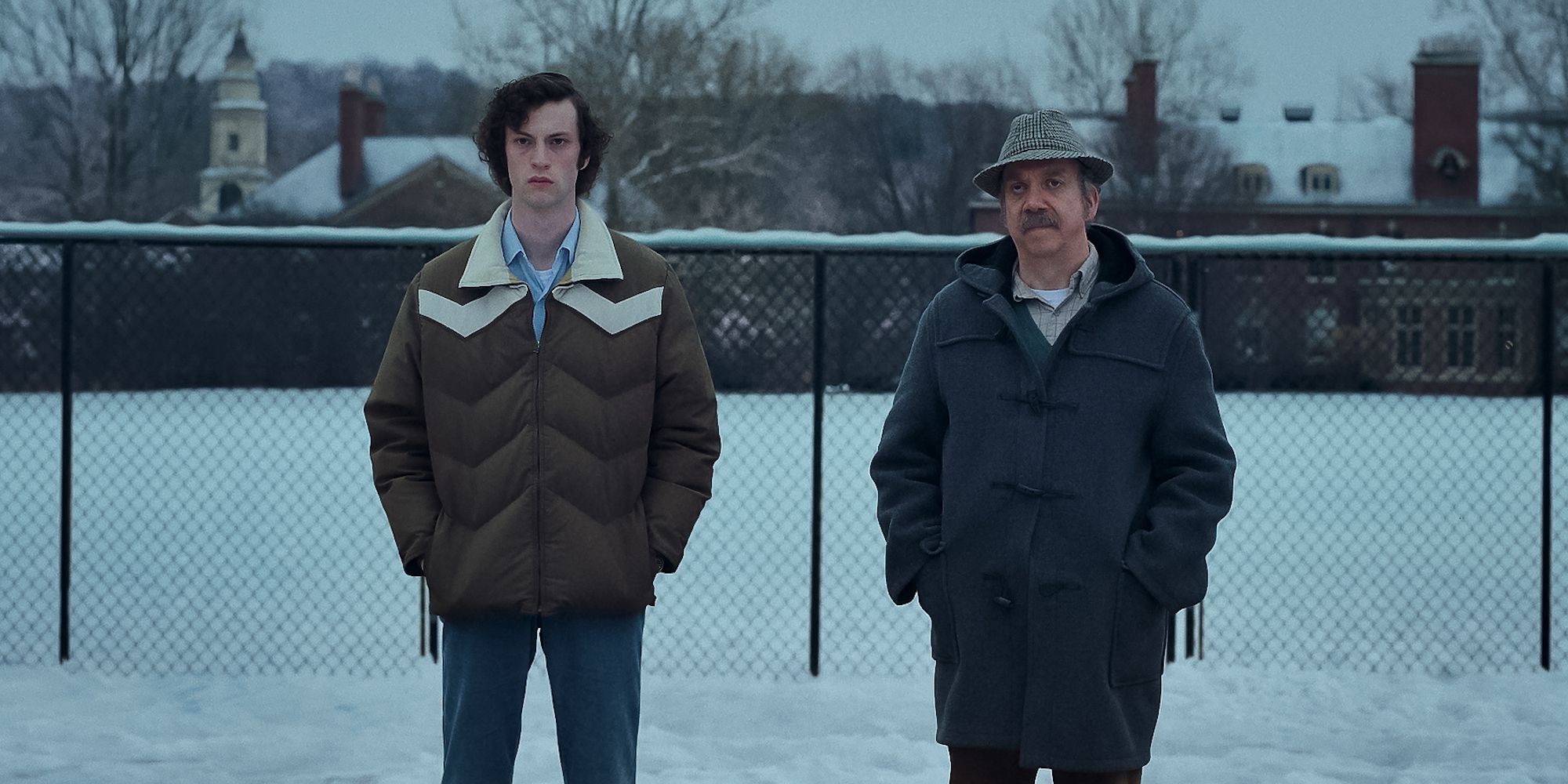 Paul Giamatti and Dominic Sessa as Angus and Paul standing in snow in The Holdovers