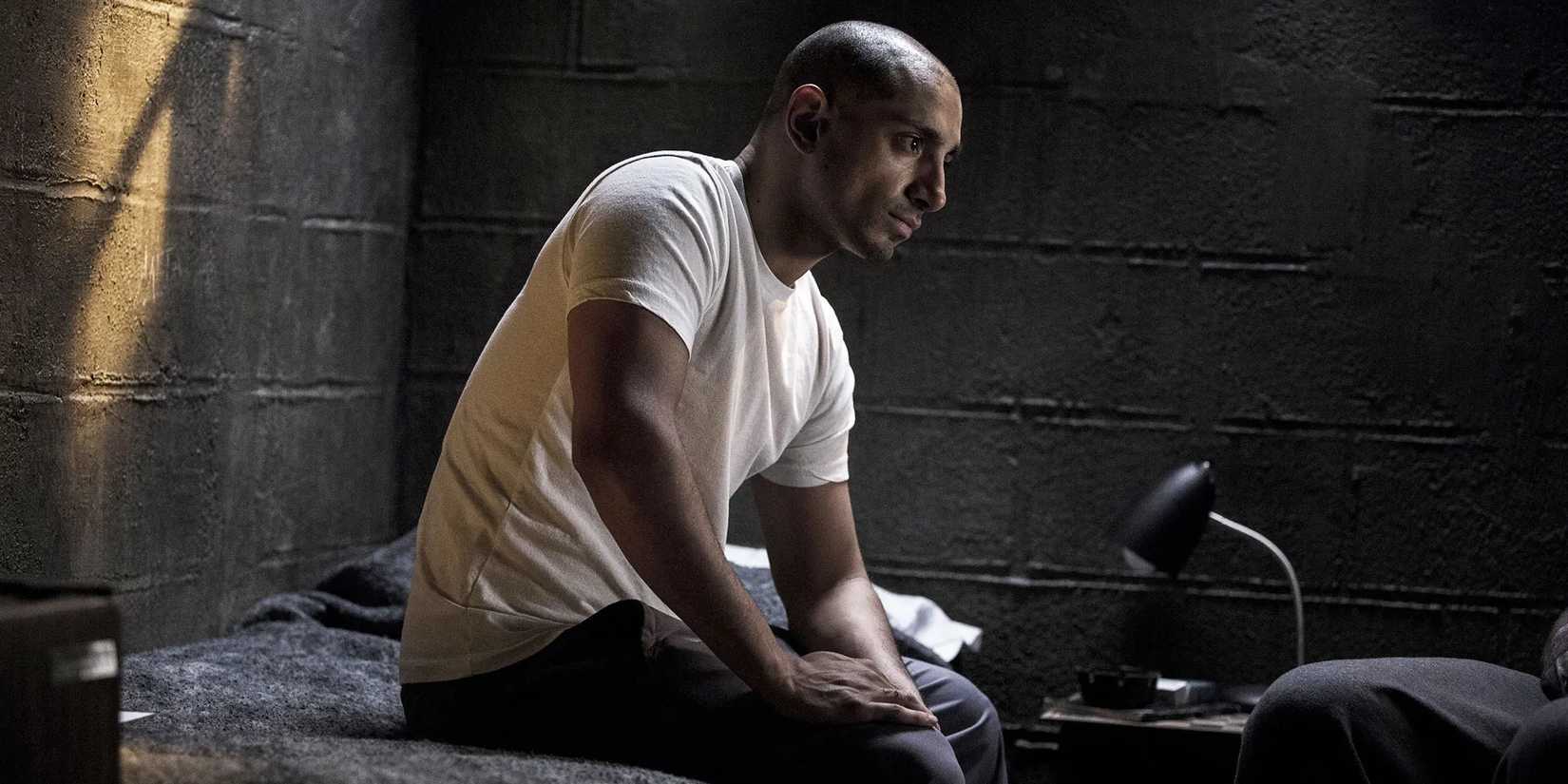 Riz Ahmed as Nasir 'Naz' Khan, sitting in a prison cell and staring blankly ahead in The Night Of