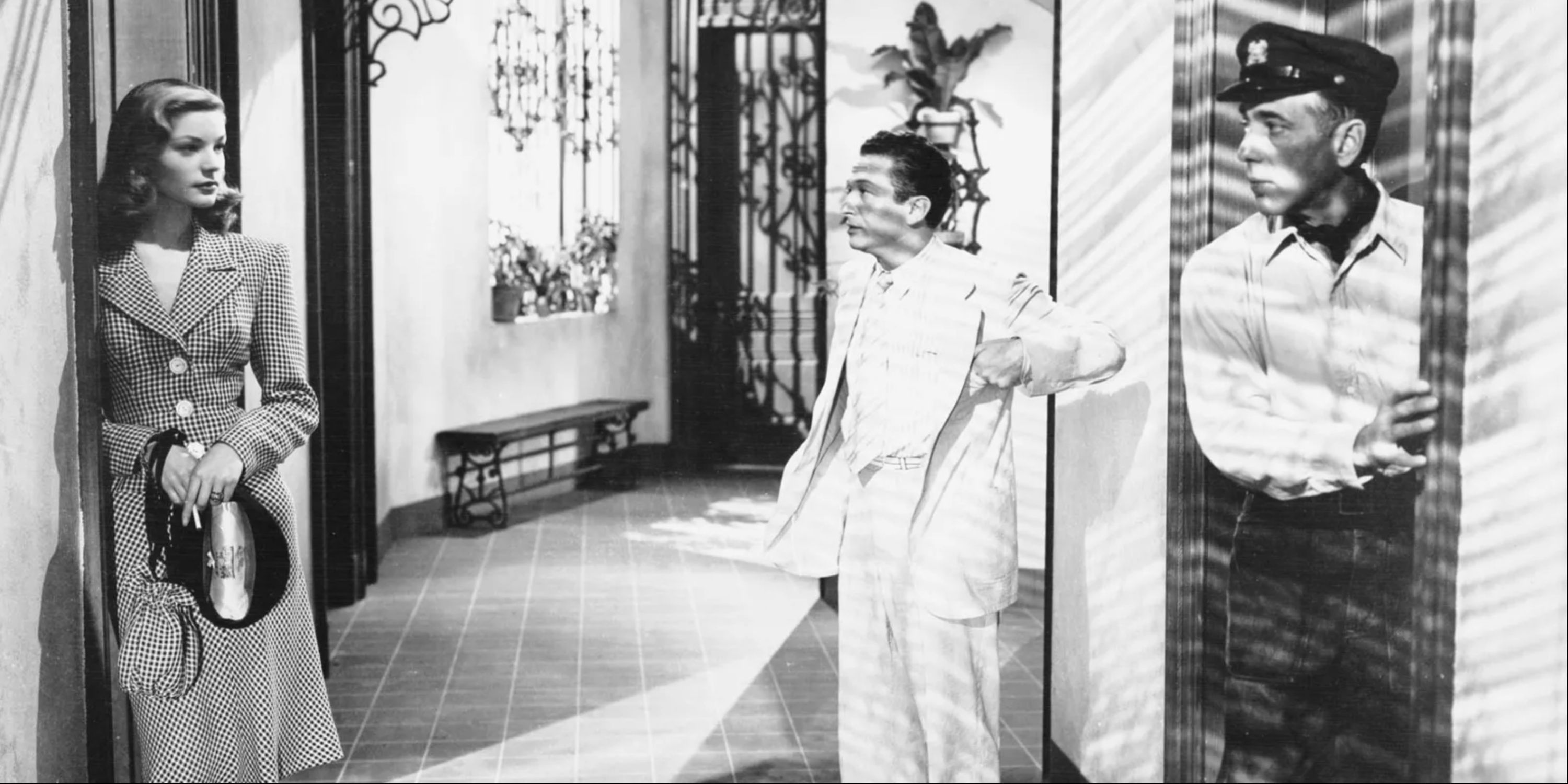 Humphrey Bogart y Luarent Bacall de pie en un pasillo hablando en Tener y no tener