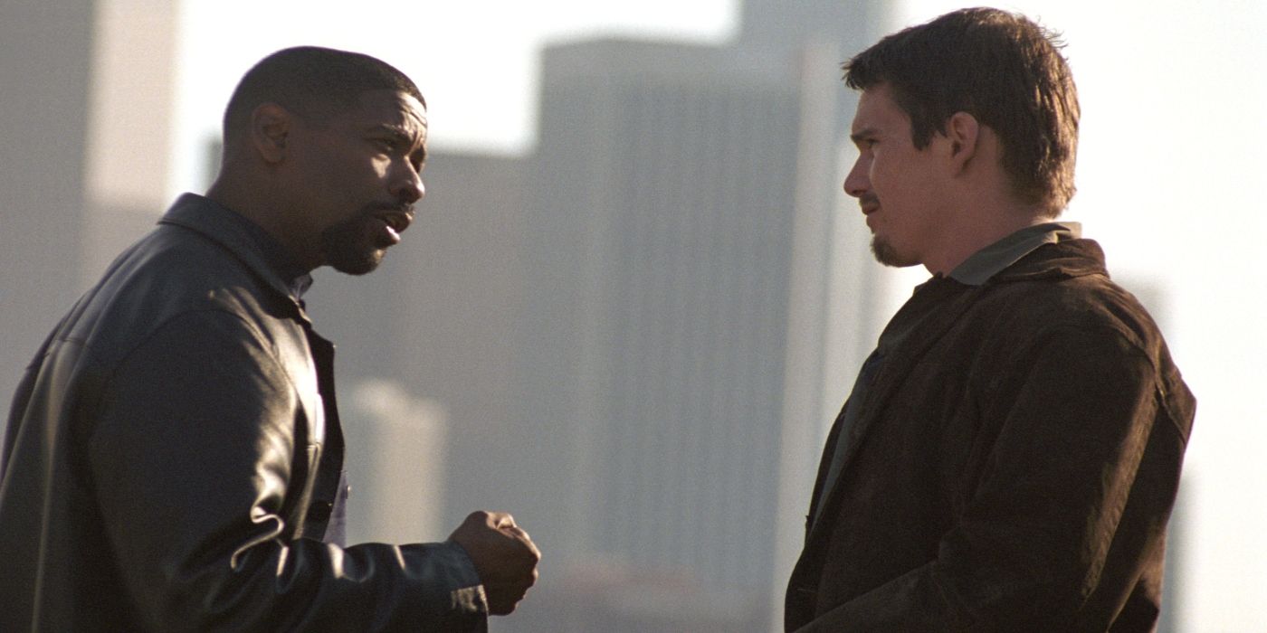 Two men have a serious conversation while a city skyline looms in the background